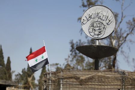 a syrian national flag flutters next to the islamic state 039 s slogan at a roundabout where executions were carried out by isis militants in the city of palmyra in homs governorate syria april 1 2016 photo reuters