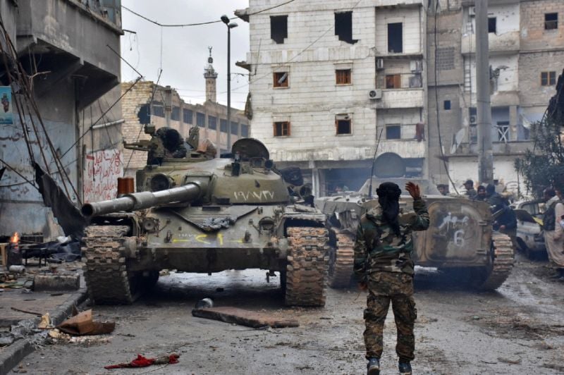 a member of the syrian pro government forces gestures to tanks as they patrol the northern embattled city of aleppo on december 14 2016 photo afp