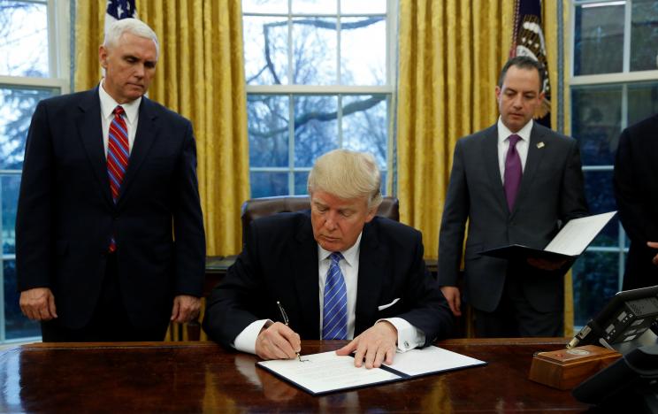 u s president donald trump signs an executive order on u s withdrawal from the trans pacific partnership while flanked by vice president mike pence l and white house chief of staff reince priebus r in the oval office of the white house in washington january 23 2017 photo reuters