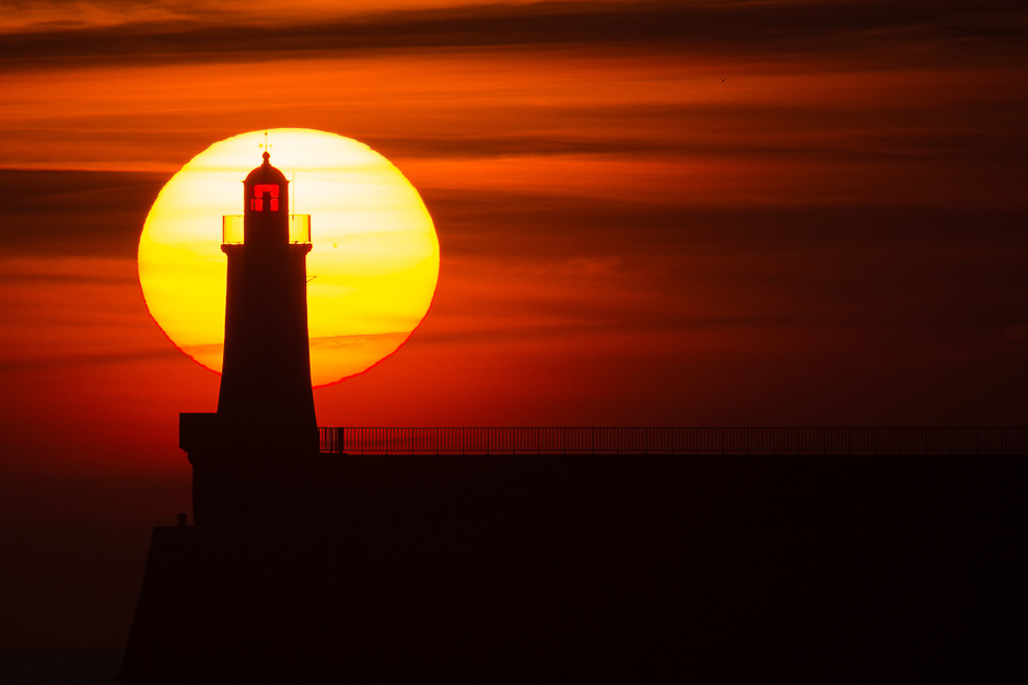 a lighthouse on a pier at sunset in les sables d 039 olonne western france photo afp