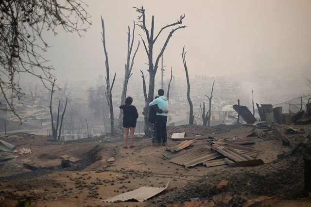 people walk amid the remains of burnt down buildings after a forest fire in santa olga 240 kilometres south of santiago on january 26 2017 photo afp people walk amid the remains of burnt down buildings after a forest fire in santa olga 240 kilometres south of santiago on january 26 2017 photo afp