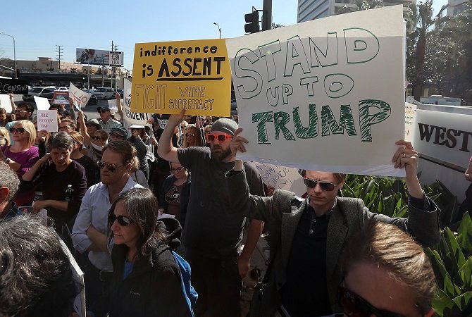 protesters hold signs during a demonstration against u s president donald trump outside the office of sen dianne feinstein d ca on january 31 2017 in los angeles california photo afp