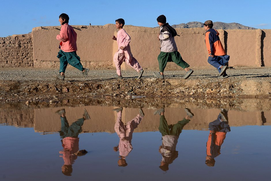 afghan youth are reflected in a pool of rainwater on the outskirts of herat photo afp