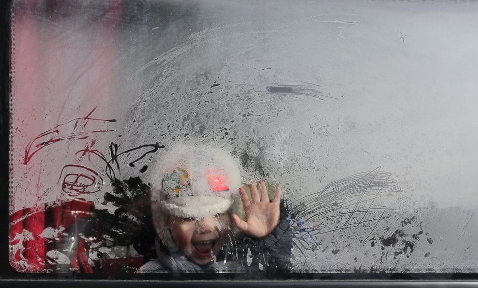 a boy waves as he sits in a bus prior to be evacuated from the ukrainian town of avdiivka photo afp