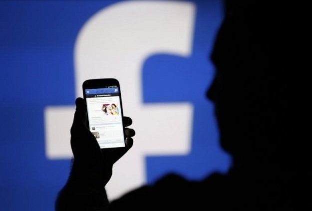 a man is silhouetted against a video screen with an facebook logo as he poses with an samsung s4 smartphone in this photo illustration taken in the central bosnian town of zenica august 14 2013 photo reuters