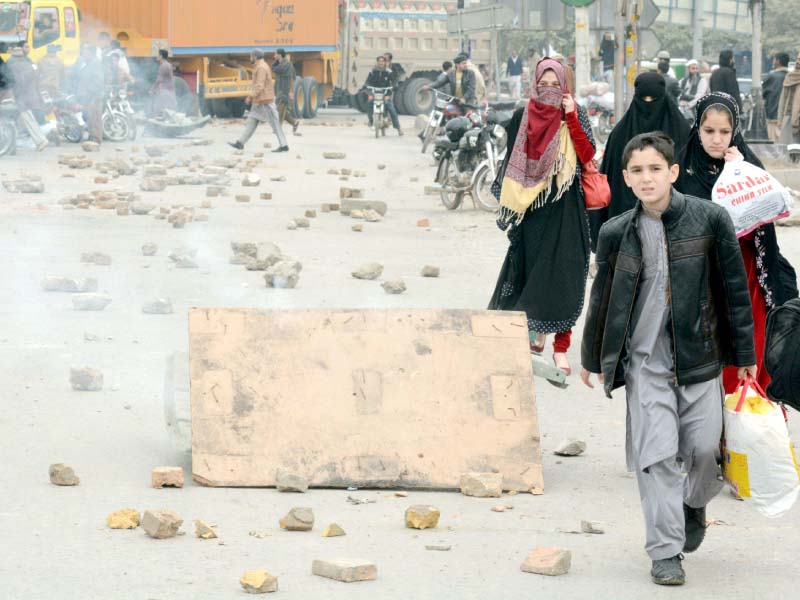 a group of children walk along a rock strewn ijp road where people protested against the police who shot a man for not stopping at a check post photo express