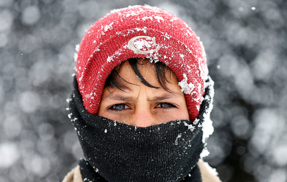 an internally displaced afghan boy looks on as he stands outside his shelter during a snowfall in kabul afghanistan photo reuters