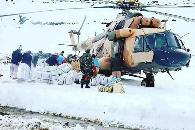 afghan survivors of an avalanche look on as an afghan army helicopter delivers relief goods in the village of hafsa in nuristan province photo afp