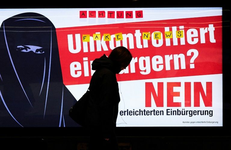 people walk by an electoral poster at zurich station which reads quot uncontrolled citizenship no quot ahead of a vote on citizenship photo afp