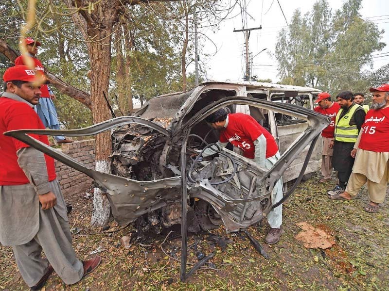 volunteers inspect the mangled heap of a van targeted in the peshawar suicide attack a photo of the three levies men killed in the mohmand bombings photo afp express