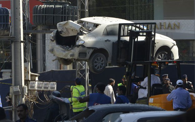 officials move a damaged car from the site after a bomb attack in lahore on february 23 2017 photo afp