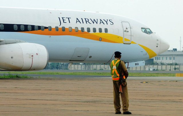 an indian security official looks on as an aircraft of jet airways taxies after landing at indira gandhi international airport in new delhi on september 12 2012 photo afp