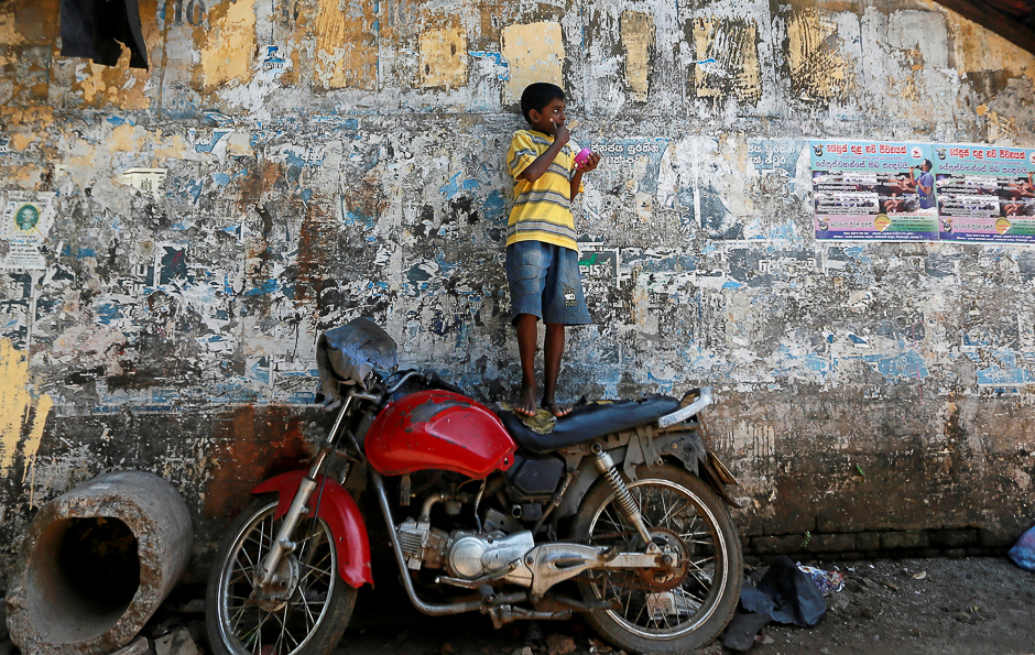 a boy eats while standing on top of a motorbike in colombo sri lanka photo reuters