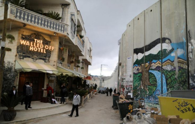 people stand outside the walled off hotel which was opened by street artist banksy in the west bank city of bethlehem march 3 2017 photo reuters people stand outside the walled off hotel which was opened by street artist banksy in the west bank city of bethlehem march 3 2017 photo reuters