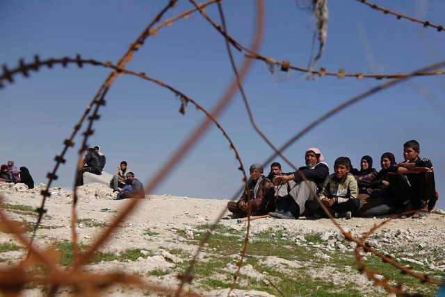 displaced iraqis sit near barbed wire as iraqi government forces supported by fighters from the abbas brigade which fight under the umbrella of the shiite popular mobilisation units advance in village of badush some 15 kilometres northwest of mosul during the ongoing battle to retake the city 039 s west from islamic state extremists on march 7 2017 photo afp