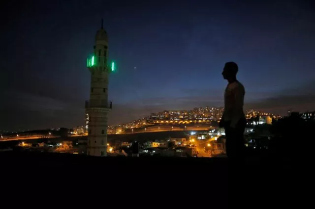 a man stands near a mosque opposite to a neighborhood in east jerusalem photo reuters a man stands near a mosque opposite to a neighborhood in east jerusalem photo reuters
