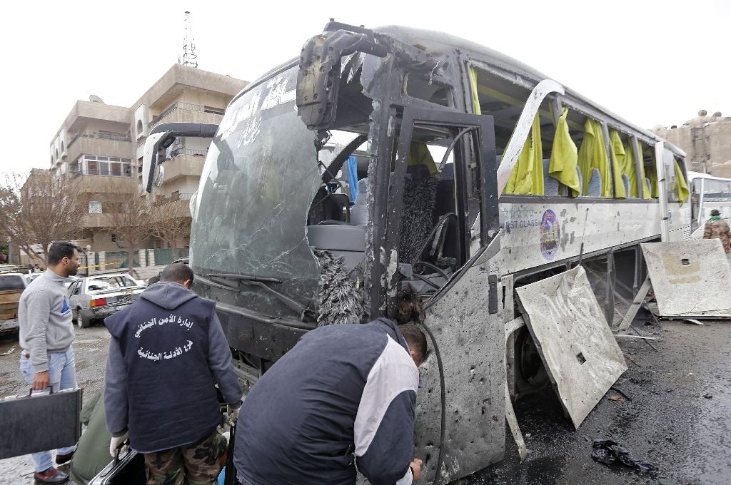 syrian forensics experts examine a damaged bus following bomb attacks in damascus 039 old city on march 11 2017 photo afp