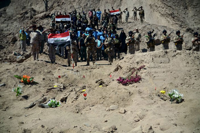 iraqi soldiers salute as they stand next to a mass grave for shia soldiers from camp speicher who have been killed by islamic state militants in the presidential compound of the former iraqi president saddam hussein in tikrit april 6 2015 photo reuters