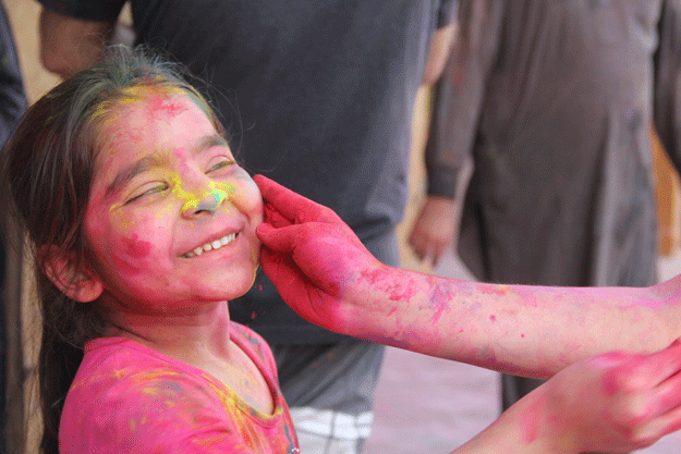 a child smiles as colour is applied to her face during holi at shri lakshmi narayan mandir photo ayesha mir