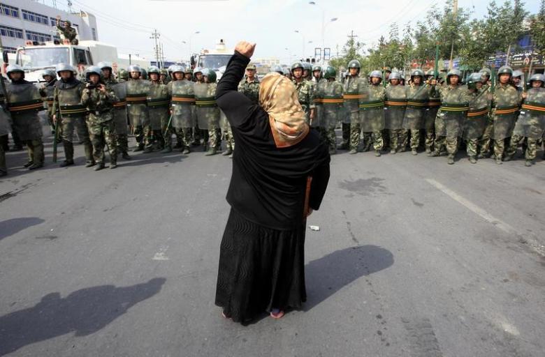 a local woman on a crutch shouts at chinese paramilitary police wearing riot gear as a crowd of angry locals confront security forces on a street in the city of urumqi in china 039 s xinjiang autonomous region photo reuters