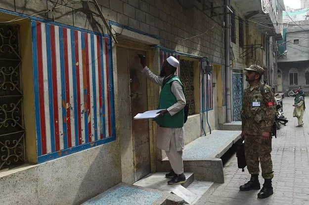 an official from the pakistan bureau of statistics l marks a house after collecting information from a resident during a census as army slodier stands guard in lahore on march 15 2017 photo afp an official from the pakistan bureau of statistics l marks a house after collecting information from a resident during a census as army slodier stands guard in lahore on march 15 2017 photo afp
