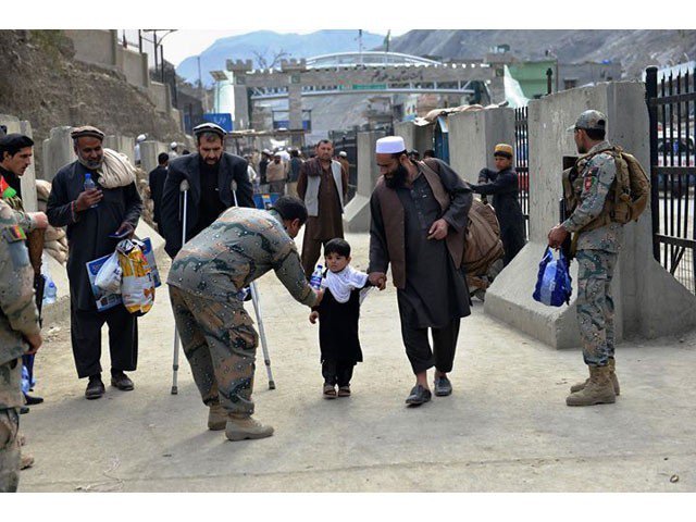 a border police personnel provides water to an afghan child who returned home after remaining stranded for 18 days photo twitter pajhwok