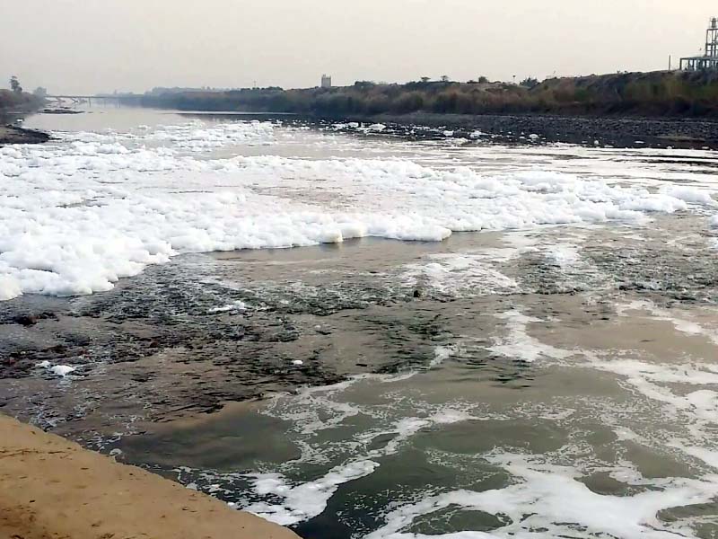 water in a canal covered with toxic white foam due to industrial waste photo express