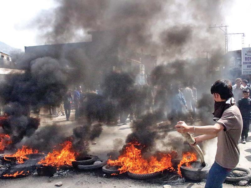 relatives of a child injured by police firing burn tires in muzaffarabad photo inp