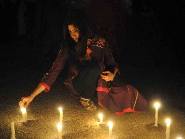 a girl lights candles in front of the parliament house to mark the sixth global earth hour in islamabad on march 31 2012 photo afp