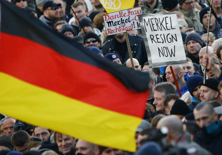 supporters of anti immigration right wing movement pegida patriotic europeans against the islamisation of the west demand the resignation of german chancellor angela merkel on a placard during a demonstration rally in cologne germany photo reuters