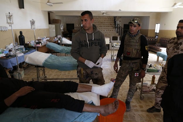 members of the iraqi forces tend to a civilian who was injured by islamic state is group militants at a school turned hospital in western mosul on march 24 2017 photo afp