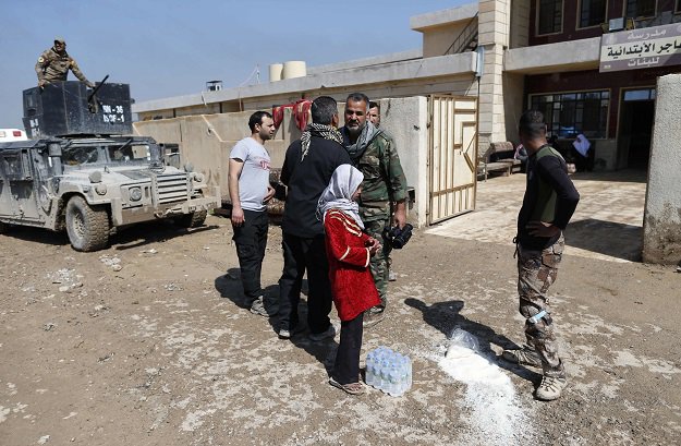 members of the iraqi forces and civilians stand outside a school turned hospital in western mosul on march 24 2017 photo afp