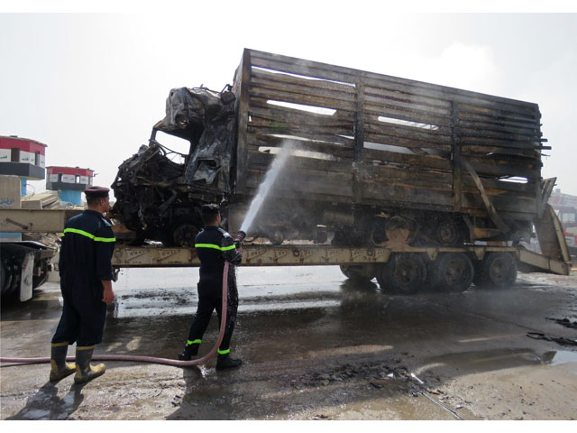 emergency services extinguish smoke rising from a truck the day after a suicide bombing targeting a checkpoint at a main southern entrance to baghdad on march 30 2017 photo afp