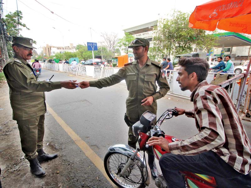 policemen check the paperwork of a motorcyclist in lahore photo abid nawaz express