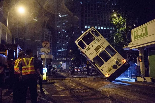 emergency service personnel watch as a double decker tram is lifted by crane after it tipped over on a main road in hong kong early on april 6 2017 photo afp emergency service personnel watch as a double decker tram is lifted by crane after it tipped over on a main road in hong kong early on april 6 2017 photo afp
