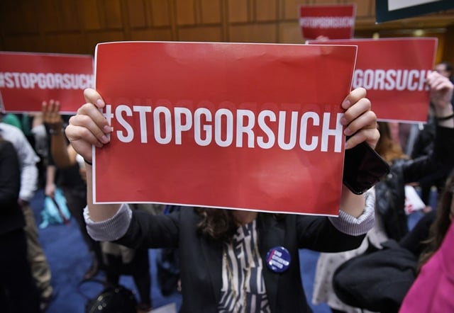 activists hold placards during a press confernce by democratic senators against the nomination of judge neil gorsuch to the supreme court in the hart senate office building on april 6 2017 in washington dc photo afp