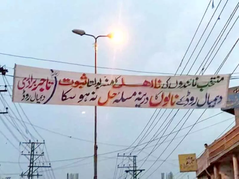 the banner reads that local government representatives have yet to resolve the issue of drains on damial road photo express the banner reads that local government representatives have yet to resolve the issue of drains on damial road photo express