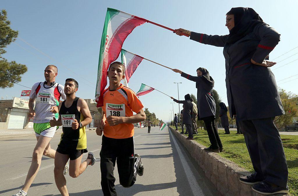 iranian women wave their national flag as they support iranian and foreign runners competing in iran 039 s first internation marathon in marvdasht on april 9 2016 photo afp