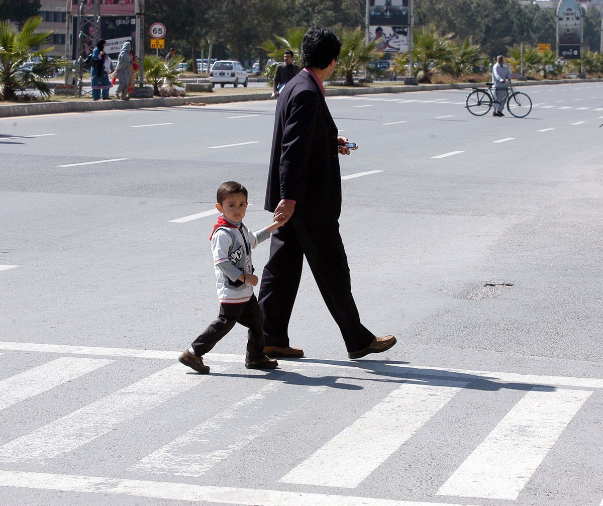 a boy and his father walk over a zebra crossing photo muhammad javaid