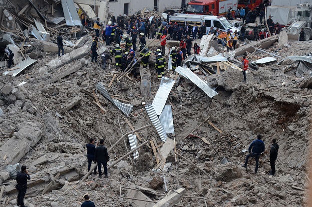 people and emergency workers stand at the site of a strong blast near the riot police headquarters in the center of diyarbakir southeastern turkey on april 11 2017 photo afp