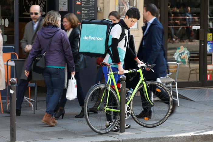 a cyclist prepares to mount a bicycle as he delivers a food order for deliveroo an example of the emergence of what is known as the 039 gig economy 039 in paris france photo reuters