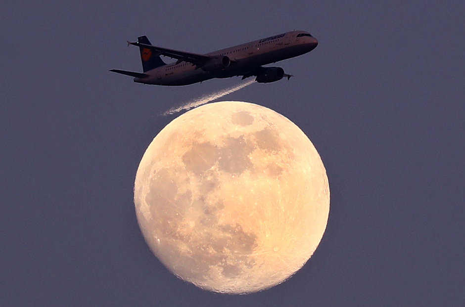 an airplane of german air carrier lufthansa passes the moon over frankfurt germany photo reuters