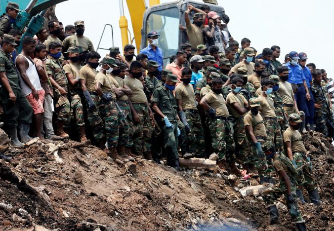 members of the military wait until another rescue team recovers a dead victim during a rescue mission after a garbage dump collapsed and buried dozens of houses in colombo sri lanka april 16 2017 photo reuters