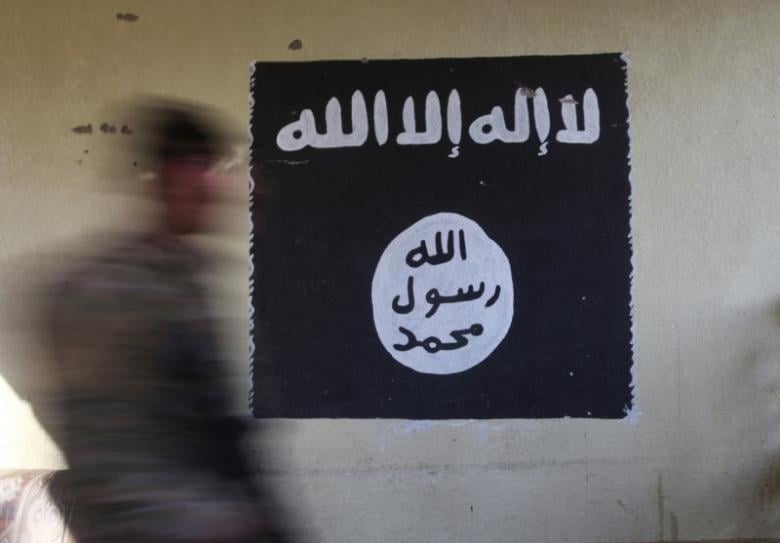 a member of the iraqi rapid response forces walks past a wall painted with the black flag commonly used by islamic state militants at a hospital damaged by clashes during a battle between iraqi forces and islamic state militants in the wahda district of eastern mosul iraq january 8 2017 photo reuters