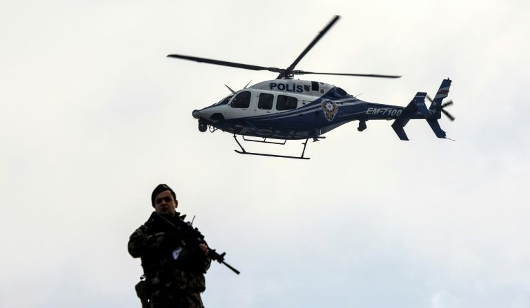 a police helicopter flies over a member of security forces near a courthouse in mugla western turkey on february 20 2017 photo afp