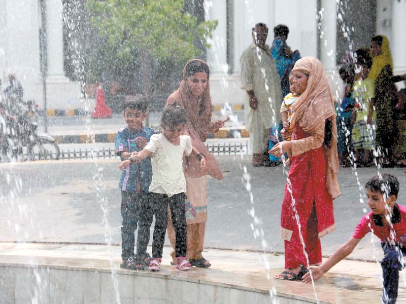 children and their families try to get some reprieve from the scorching heat in lahore by crowding a fountain on mall road photo abid nawaz express