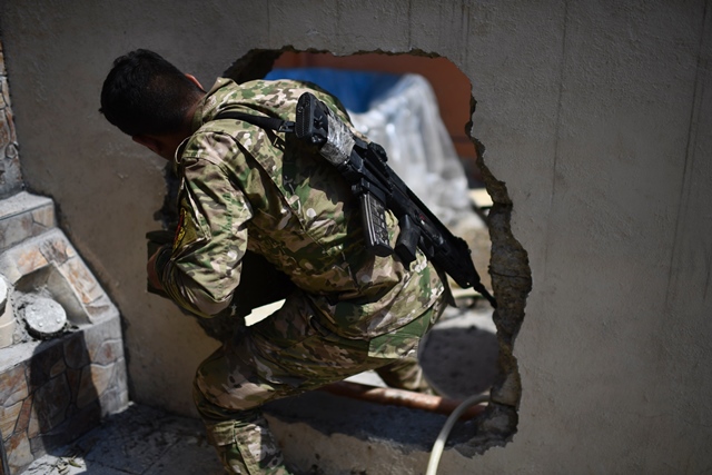 a member of the iraqi forces from the elite rapid response division makes his way through a hole in a wall during their advance in western mosul on april 19 2017 as part of their campaign to retake the city from islamic state is group fighters photo afp