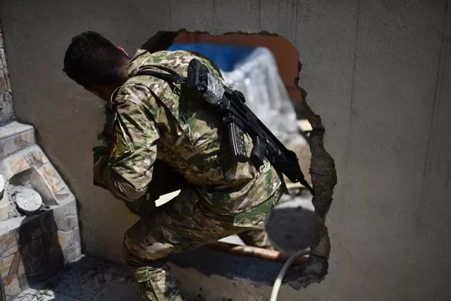 a member of the iraqi forces from the elite rapid response division makes his way through a hole in a wall during their advance in western mosul on april 19 2017 as part of their campaign to retake the city from islamic state is group fighters photo afp