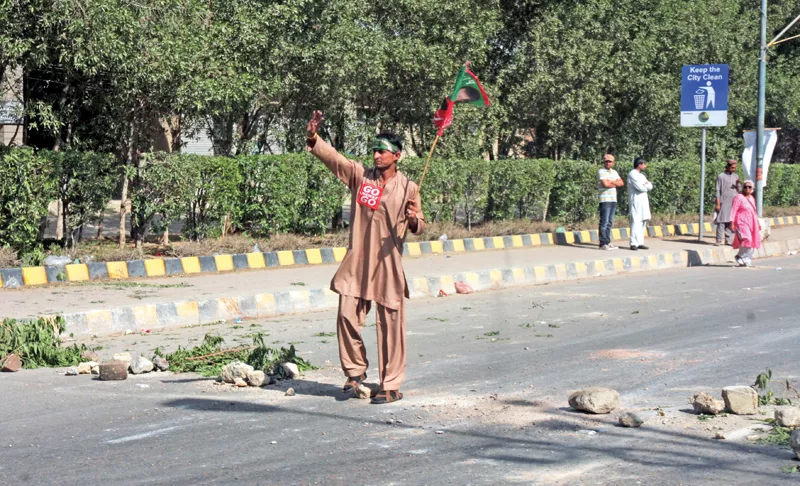 a supporter of pti holds the party flag at a sit in near sharae faisal photo express a supporter of pti holds the party flag at a sit in near sharae faisal photo express