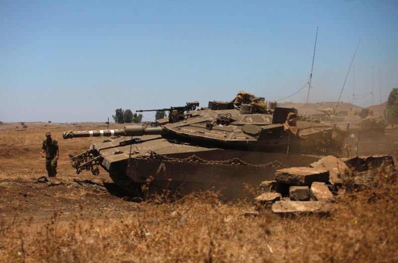 an israeli soldier directs a merkava tank stationed in the israeli annexed golan heights near the quneitra crossing with syria photo afp